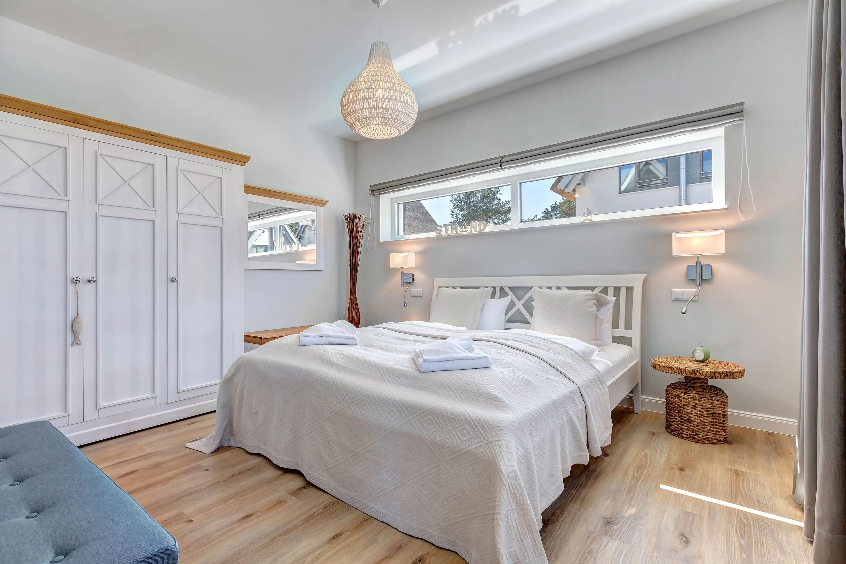 Helles Schlafzimmer mit Doppelbett, weißem Kleiderschrank und Holzboden